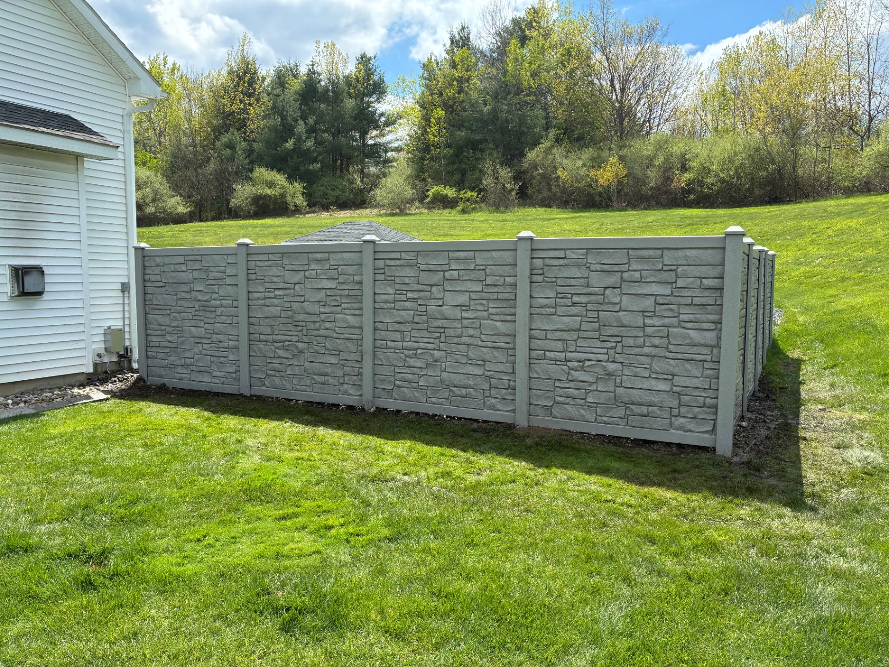 Stone-textured privacy fence installed alongside a Capital Region home